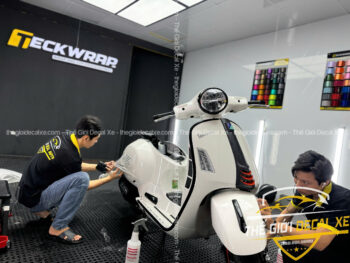 Kỹ thuật viên đang tỉ mỉ dán PPF TPU cho phần hông xe Vespa GTS đảm bảo không lộ mép dán